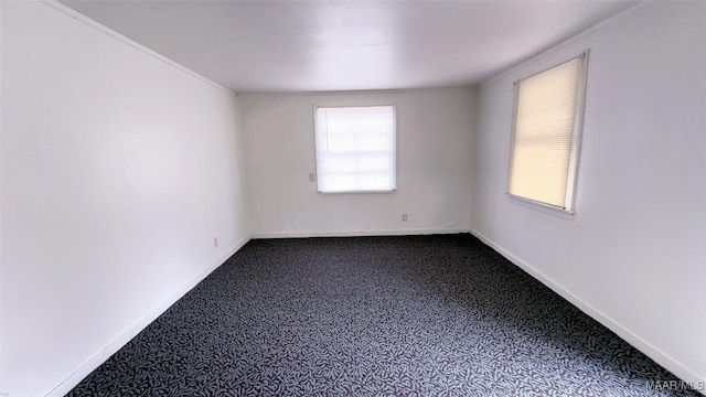 empty room featuring dark colored carpet and baseboards