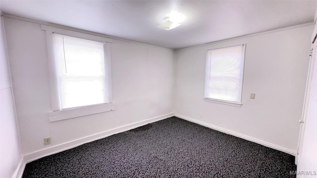 unfurnished room featuring baseboards, dark colored carpet, and plenty of natural light