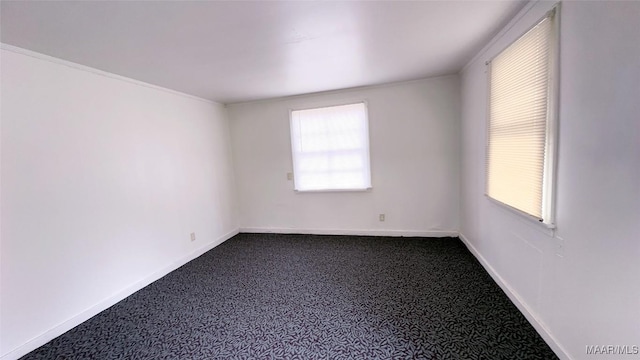 empty room with dark carpet, baseboards, and plenty of natural light