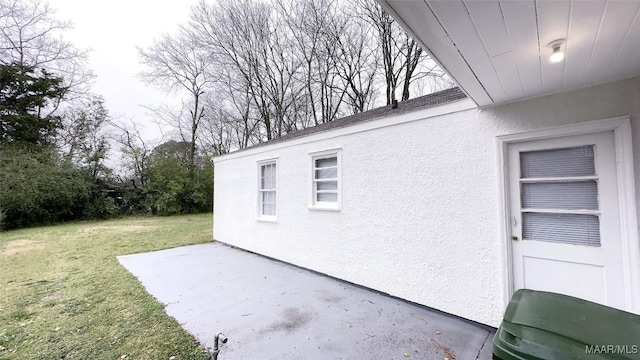 view of property exterior featuring a patio area, stucco siding, and a lawn