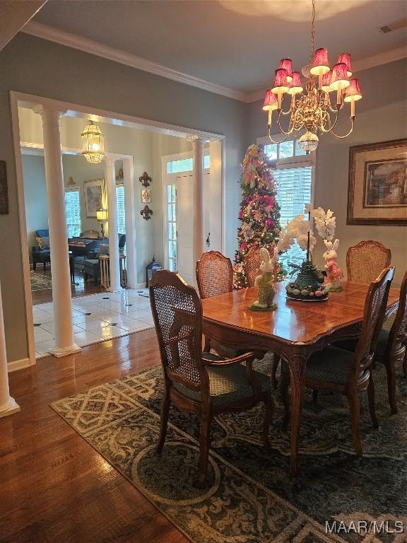 dining area with a chandelier, decorative columns, crown molding, and wood finished floors