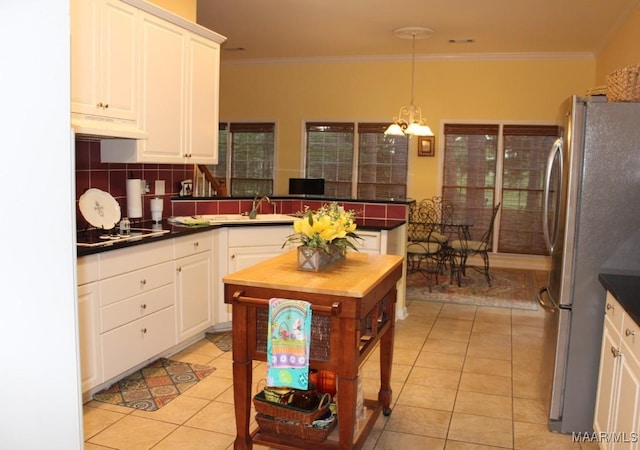 kitchen featuring light tile patterned floors, white cabinetry, freestanding refrigerator, dark countertops, and a sink