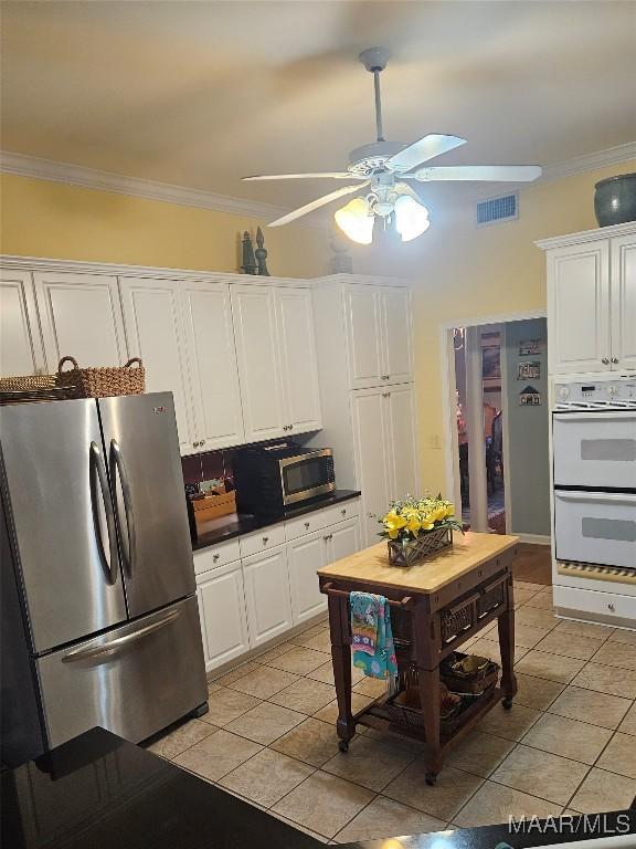 kitchen featuring visible vents, appliances with stainless steel finishes, a ceiling fan, crown molding, and white cabinetry