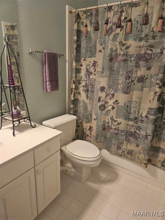 bathroom featuring tile patterned floors, shower / bath combo with shower curtain, vanity, and toilet
