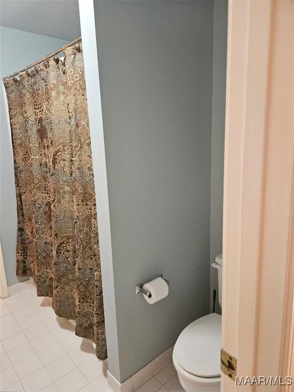 bathroom with toilet, a shower with shower curtain, and tile patterned flooring