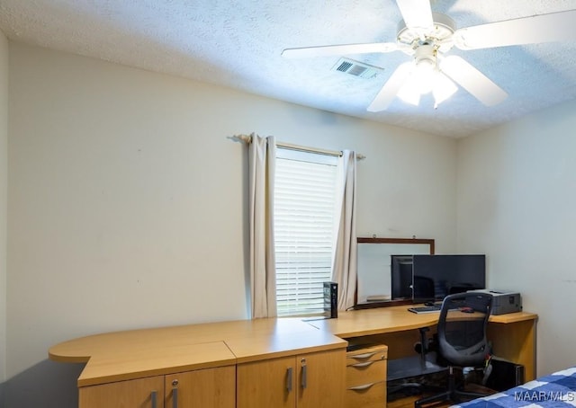office space featuring visible vents, a ceiling fan, and a textured ceiling