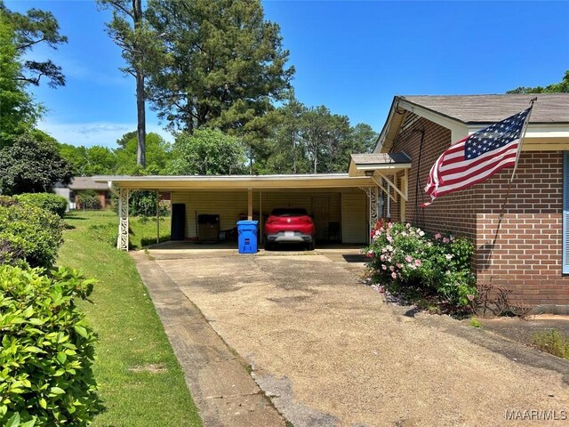 view of side of home with concrete driveway, a carport, and brick siding