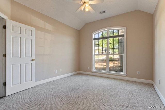 carpeted spare room with visible vents, baseboards, a ceiling fan, and vaulted ceiling