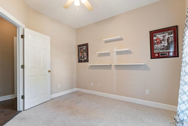 carpeted empty room featuring baseboards and a ceiling fan