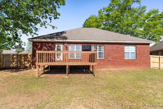 back of house with brick siding, a fenced backyard, a deck, and a lawn