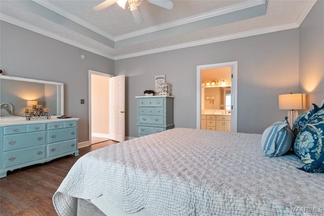 bedroom with ensuite bath, dark wood-style floors, crown molding, and a raised ceiling