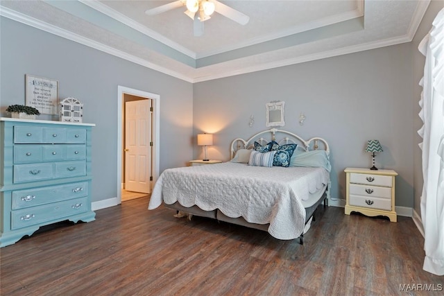 bedroom with dark wood-type flooring, a tray ceiling, baseboards, and crown molding