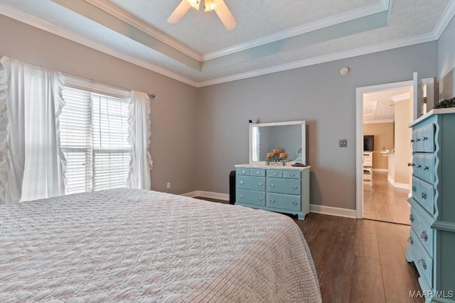 bedroom featuring baseboards, dark wood-type flooring, a tray ceiling, and ornamental molding