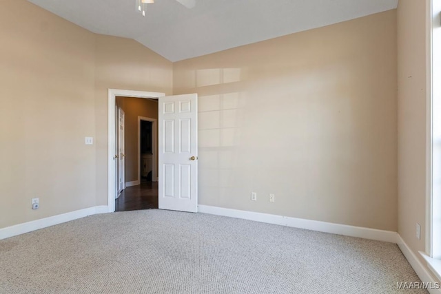 carpeted empty room with ceiling fan, baseboards, and vaulted ceiling