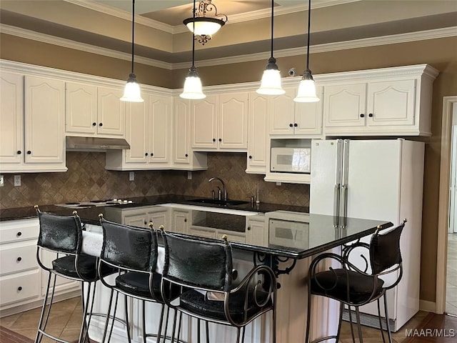 kitchen featuring dark countertops, white appliances, under cabinet range hood, and a sink