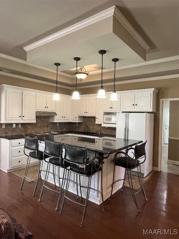 kitchen with white cabinets, dark countertops, and white appliances