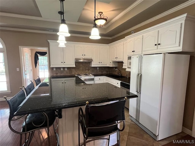 kitchen with under cabinet range hood, white appliances, white cabinetry, and crown molding