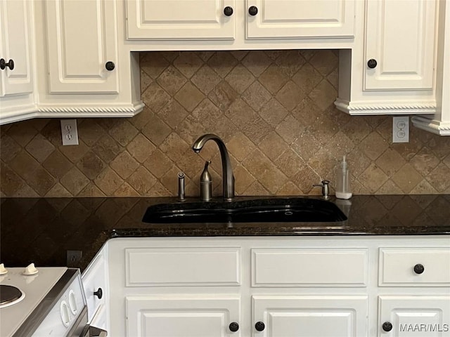 kitchen featuring white cabinets, backsplash, and a sink
