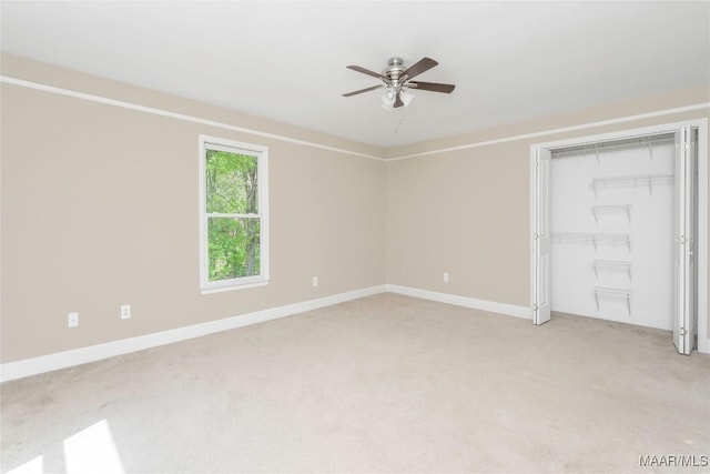 unfurnished bedroom featuring light carpet, a closet, baseboards, and a ceiling fan