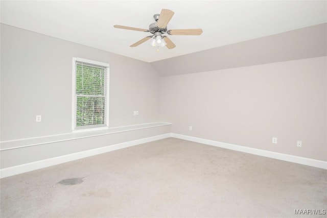 spare room with light carpet, ceiling fan, baseboards, and lofted ceiling