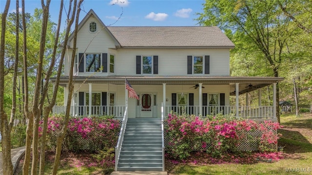 country-style home featuring covered porch, a ceiling fan, and stairs