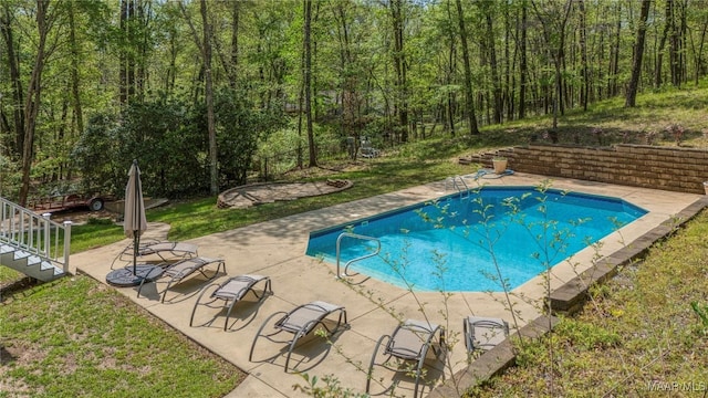 view of pool with a view of trees and a patio