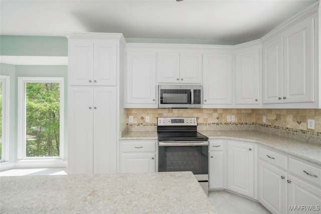 kitchen with tasteful backsplash, white cabinetry, light stone counters, and stainless steel appliances