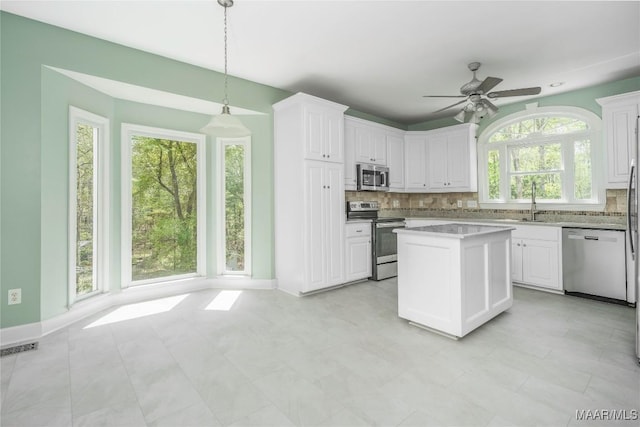 kitchen featuring tasteful backsplash, a wealth of natural light, white cabinets, and stainless steel appliances