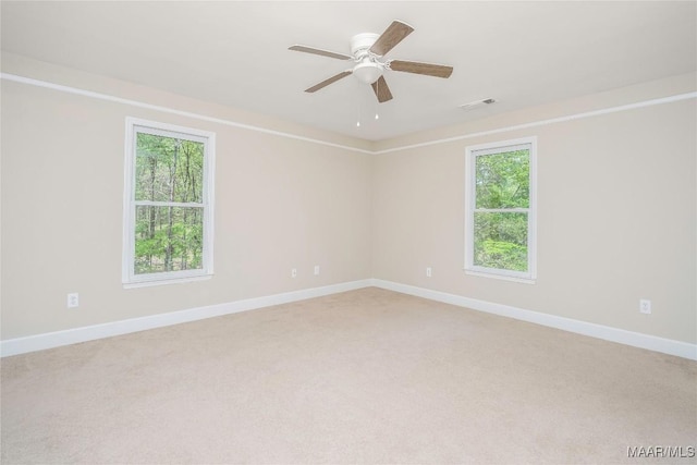 unfurnished room featuring light carpet, visible vents, baseboards, and plenty of natural light