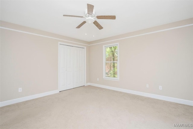 unfurnished bedroom with a closet, baseboards, a ceiling fan, and light colored carpet