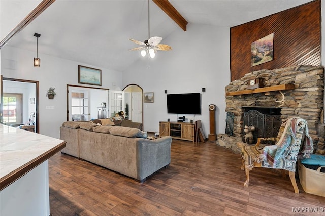 living area featuring a stone fireplace, a ceiling fan, beam ceiling, dark wood finished floors, and high vaulted ceiling