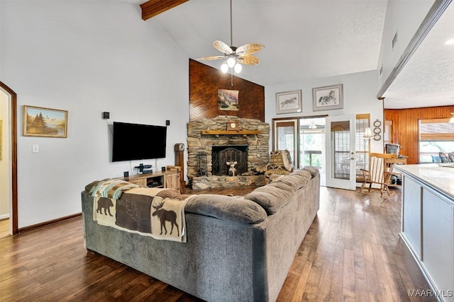 living room with baseboards, a stone fireplace, ceiling fan, hardwood / wood-style flooring, and high vaulted ceiling