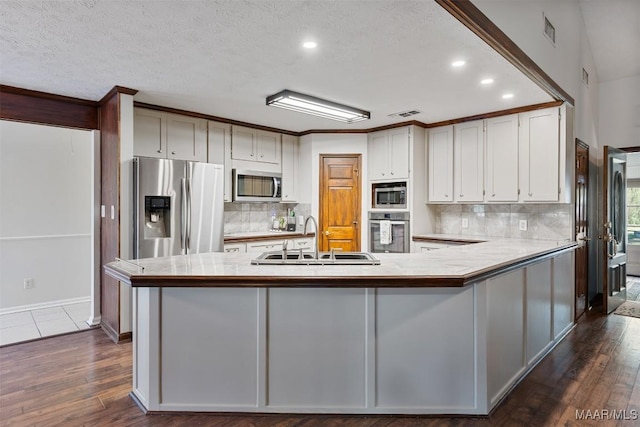 kitchen featuring visible vents, a sink, light countertops, a peninsula, and stainless steel appliances