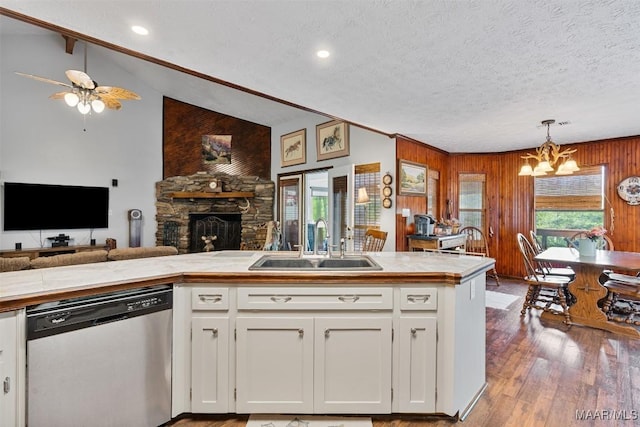 kitchen with a sink, open floor plan, white cabinetry, wood finished floors, and stainless steel dishwasher
