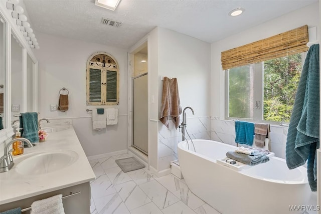 bathroom featuring a freestanding bath, double vanity, marble finish floor, and a sink