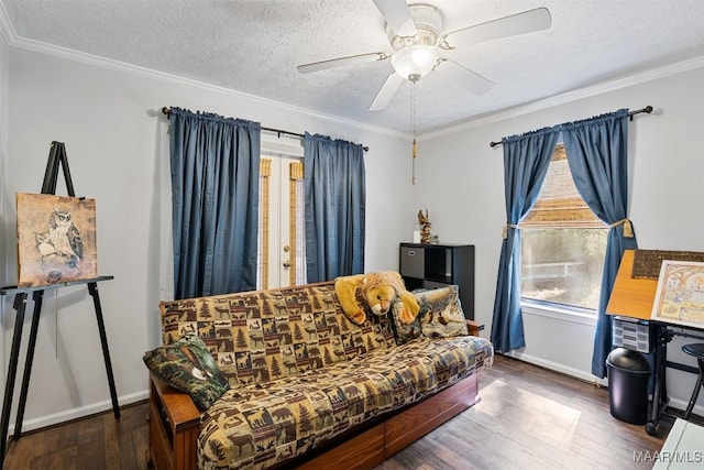 living area with a textured ceiling, ornamental molding, a ceiling fan, wood finished floors, and baseboards