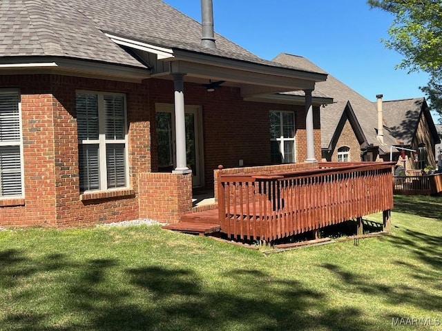 rear view of house with roof with shingles, a yard, and brick siding