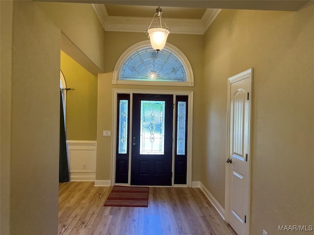 foyer entrance featuring baseboards, crown molding, and wood finished floors