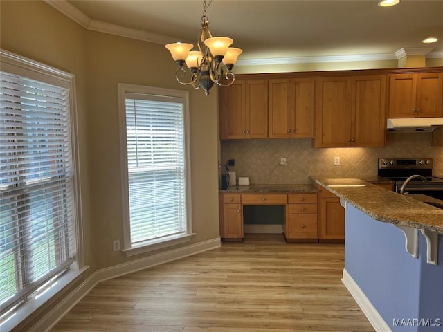 kitchen featuring a chandelier, under cabinet range hood, light wood-type flooring, and ornamental molding