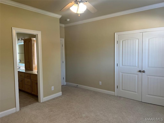 unfurnished bedroom featuring baseboards, a closet, ornamental molding, light carpet, and ensuite bath