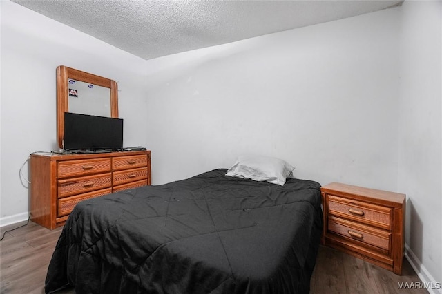 bedroom with baseboards, wood finished floors, and a textured ceiling
