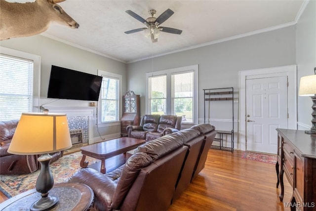 living area with ceiling fan, ornamental molding, and wood finished floors
