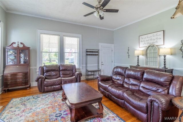 living area featuring wood finished floors, ornamental molding, and a ceiling fan