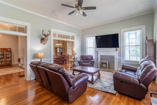 living room featuring visible vents, ornamental molding, a ceiling fan, wood finished floors, and a tile fireplace