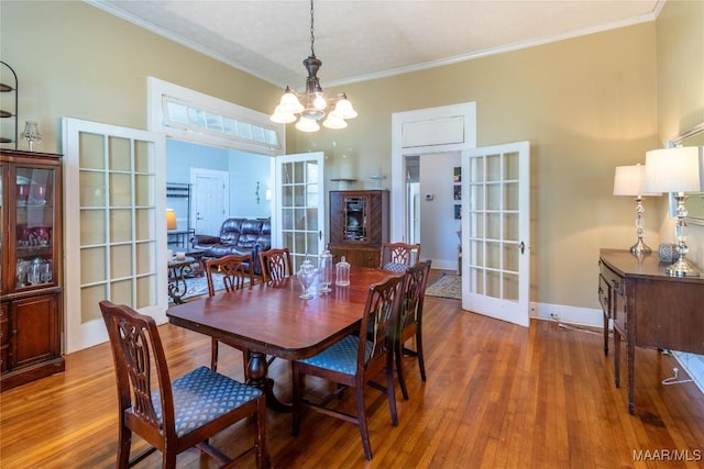 dining area featuring baseboards, ornamental molding, a chandelier, wood finished floors, and french doors