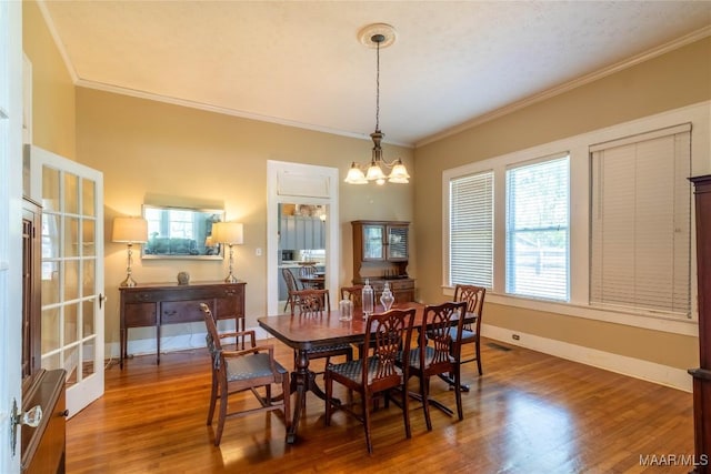 dining space featuring wood finished floors, baseboards, ornamental molding, and visible vents