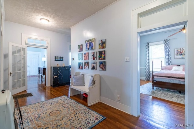 corridor with a textured ceiling, baseboards, crown molding, and wood finished floors