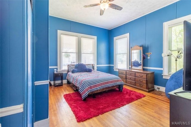 bedroom with ceiling fan, multiple windows, wood finished floors, and baseboards