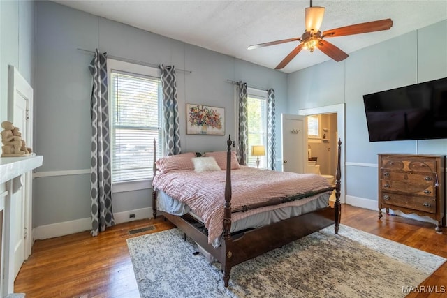 bedroom featuring visible vents, baseboards, a ceiling fan, connected bathroom, and wood finished floors