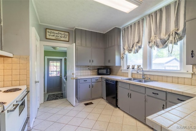 kitchen with light tile patterned floors, a sink, tile counters, black appliances, and gray cabinets